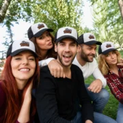 Five friends wearing black and white foam trucker hats embroidered with the Oh My Hats logo outdoors