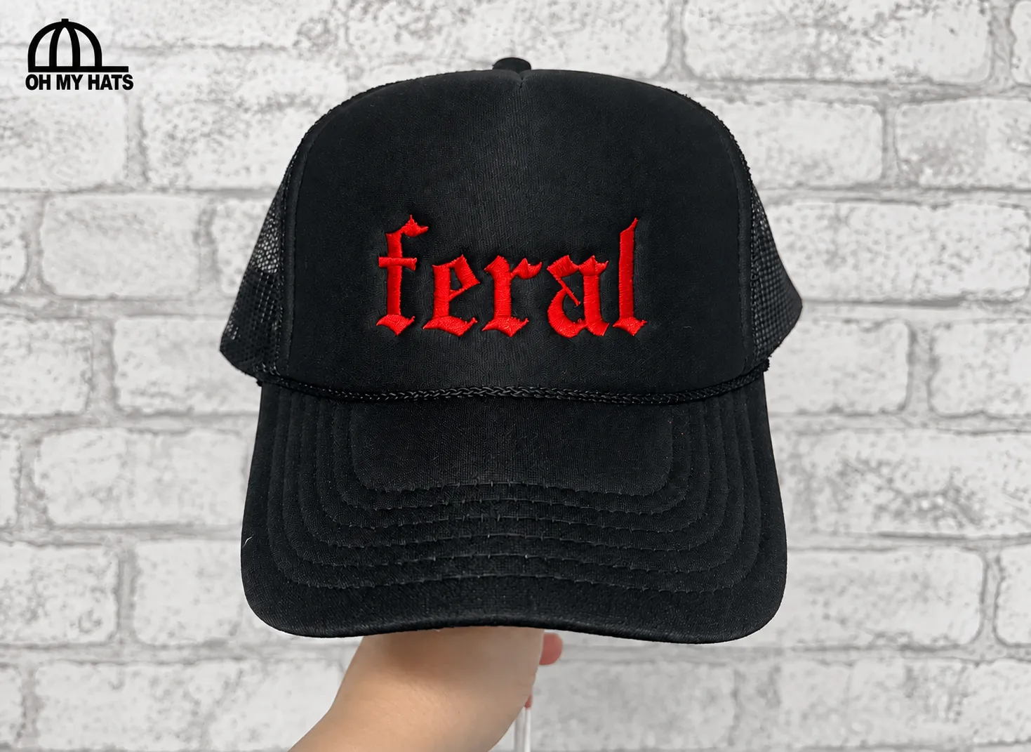 Black trucker hat with red feral embroidery and a braided rope above the brim.