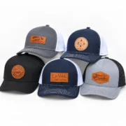 Five black, navy and gray trucker hats with custom orange leather logo patches