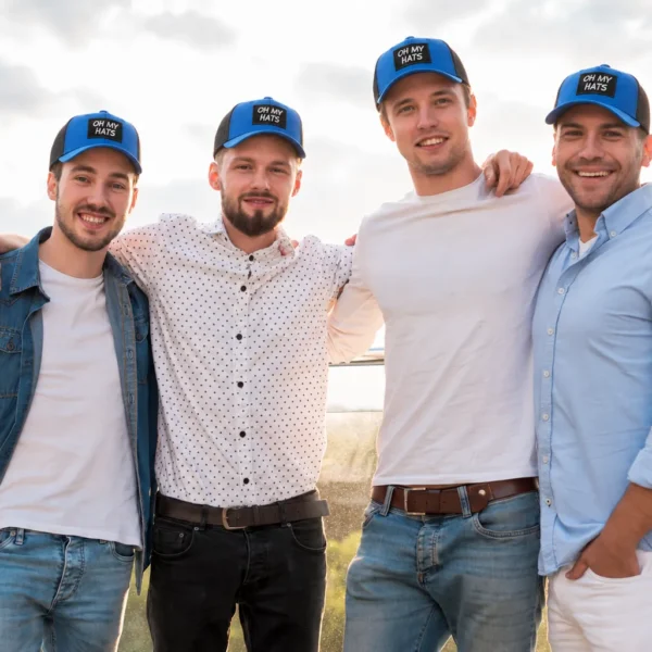 Four men wearing matching blue and black OH MY HATS patch trucker caps outdoors