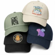 Four stacked custom printed baseball hats in cream, sage green, black, and navy.
