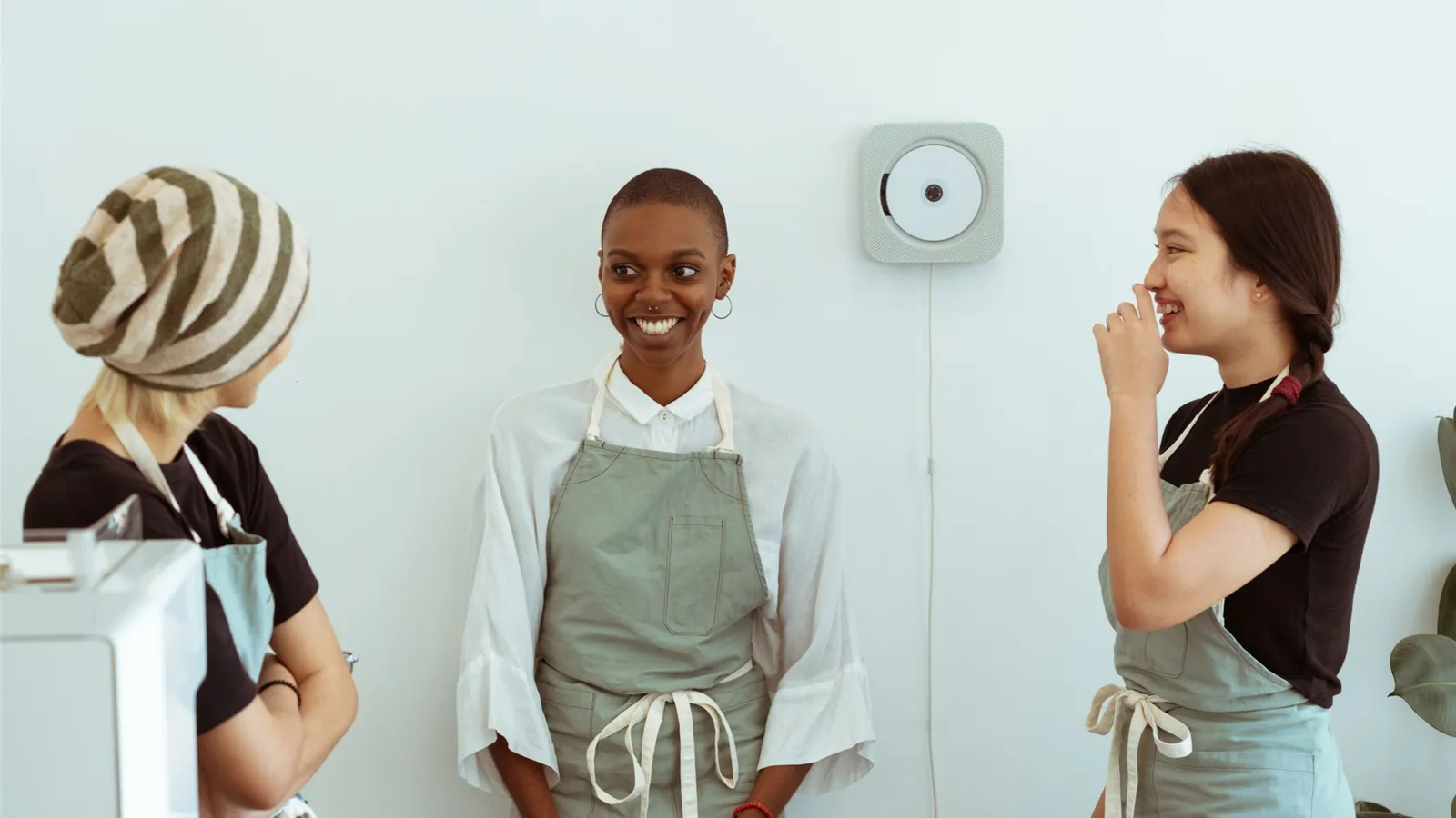 Café coworkers wearing neutral aprons and casual clothing behind a counter.