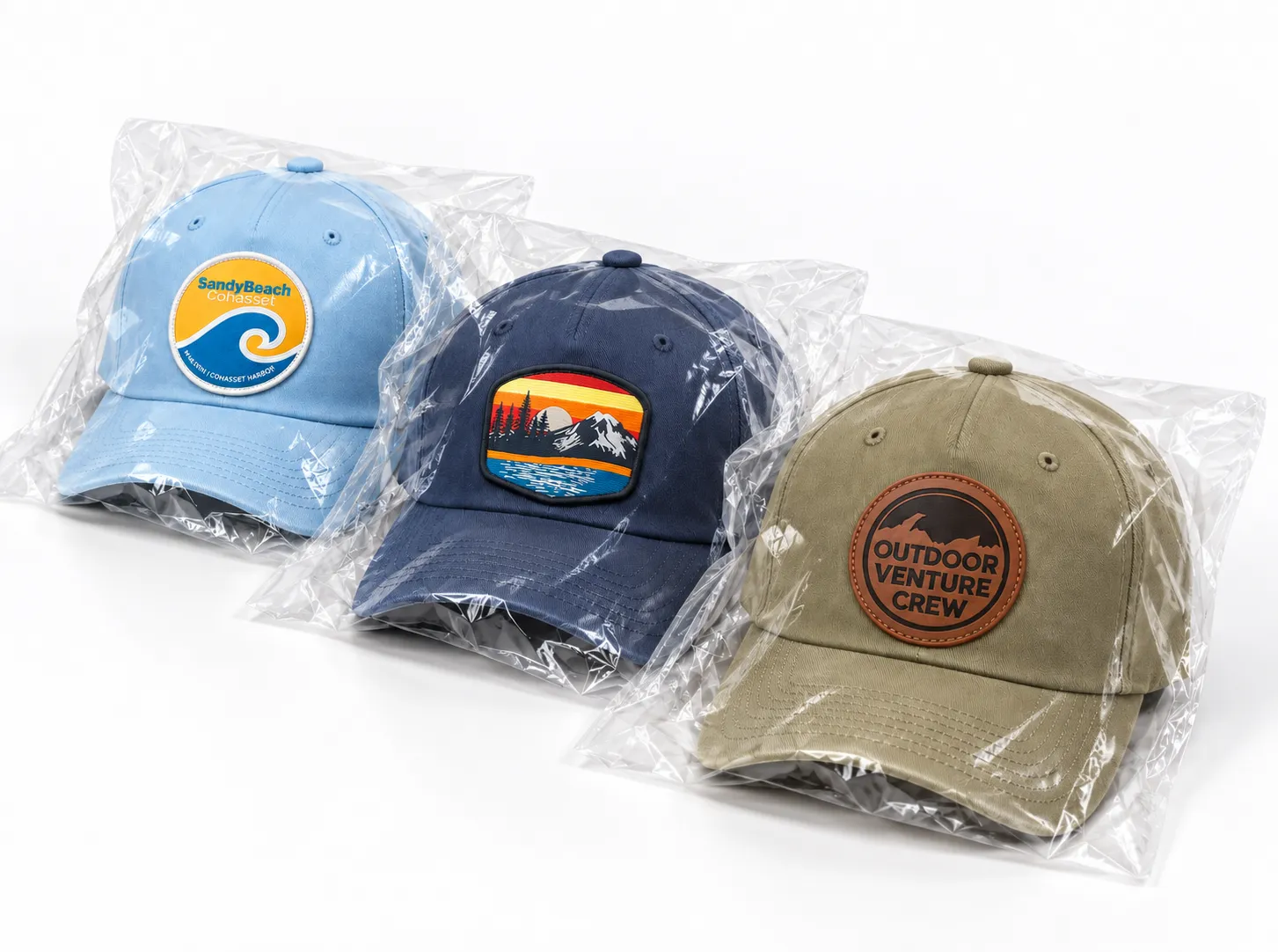 Light blue, navy and olive five-panel patch baseball hats individually packaged in clear bags on a white background.