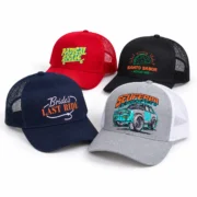 Four printed trucker hats in navy, red, black, and gray with white mesh, arranged on a white background.
